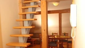 Escada de madeira que leva a uma área de jantar, com um telefone na parede.