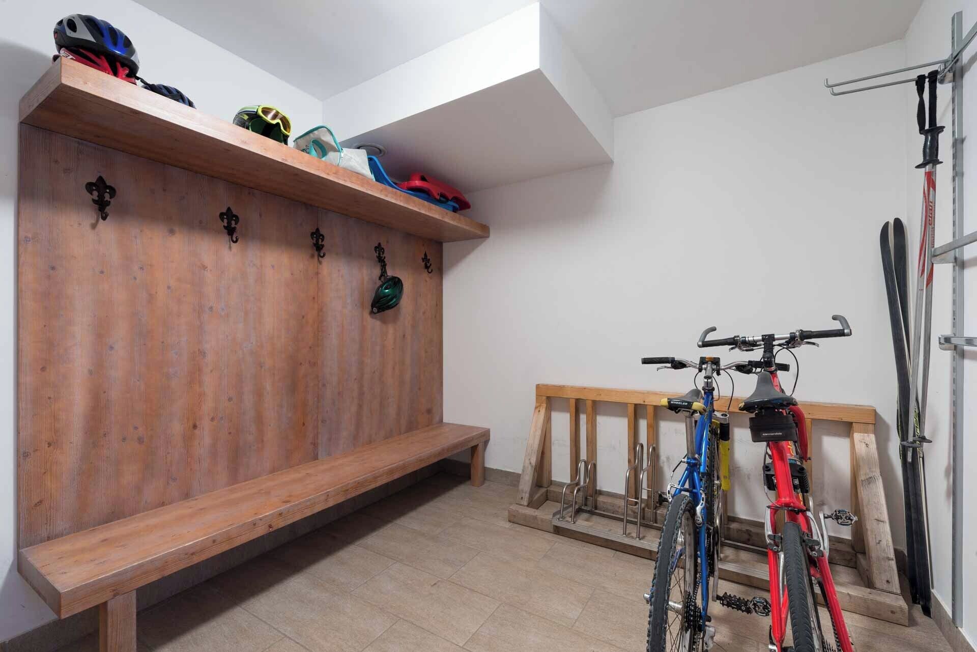 A room with a wooden bench, wall-mounted hooks, and a bike rack.