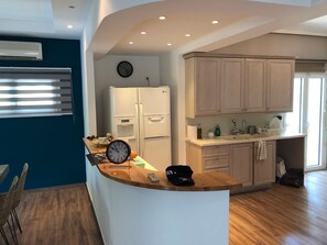 A modern kitchen with a built-in island, white appliances, and light wood cabinetry. - Casa Panorama in Voula - Panoramic Sea View Villa (Vari-Voula-Vouliagmeni)