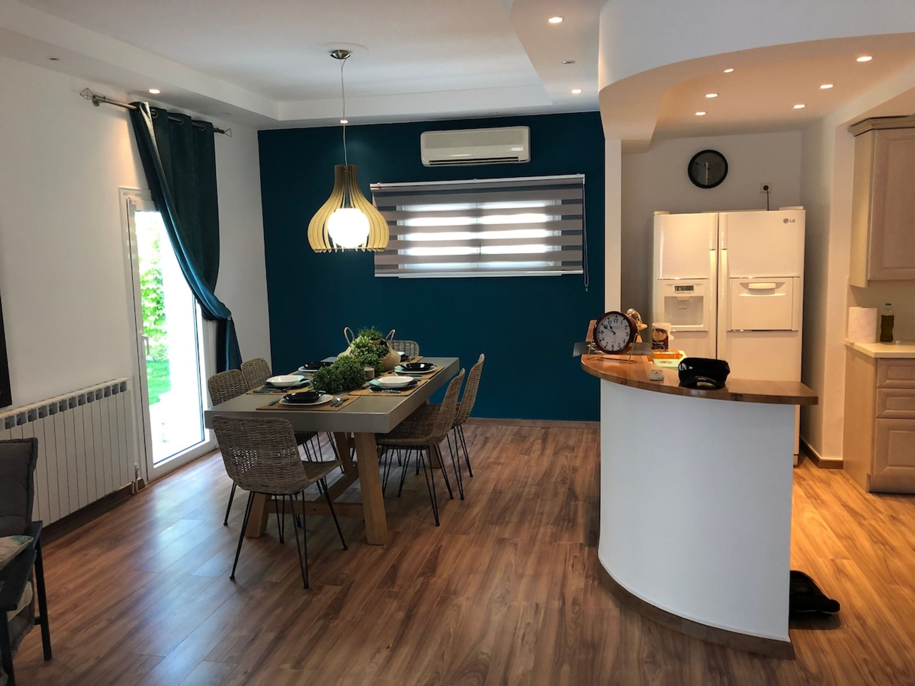 A modern kitchen with white cabinets, a built-in oven, and a clock on the wall.