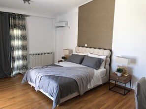 A bedroom with a bed, bedside tables, a radiator, and a wall-mounted air conditioner. - Casa Panorama in Voula - Panoramic Sea View Villa (Vari-Voula-Vouliagmeni)
