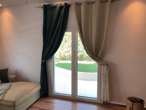 A room with a bed, a window with curtains, and a view of a green landscape. - Casa Panorama in Voula - Panoramic Sea View Villa (Vari-Voula-Vouliagmeni)