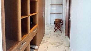 Un pasillo con un armario de madera, una silla y piso de baldosas.
