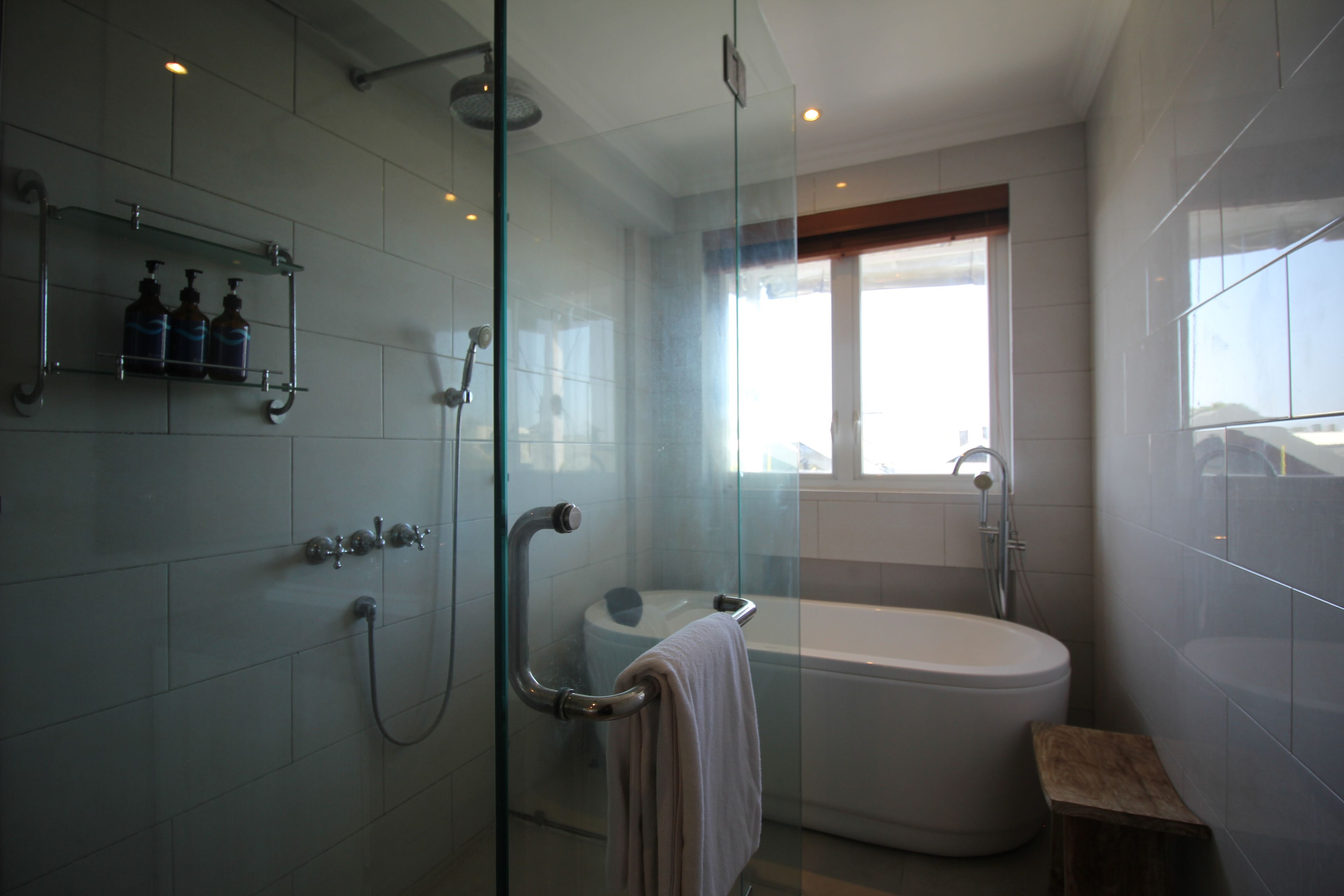 Un bagno moderno con doccia vetrata, una vasca da bagno indipendente e una finestra che permette l'illuminazione naturale.