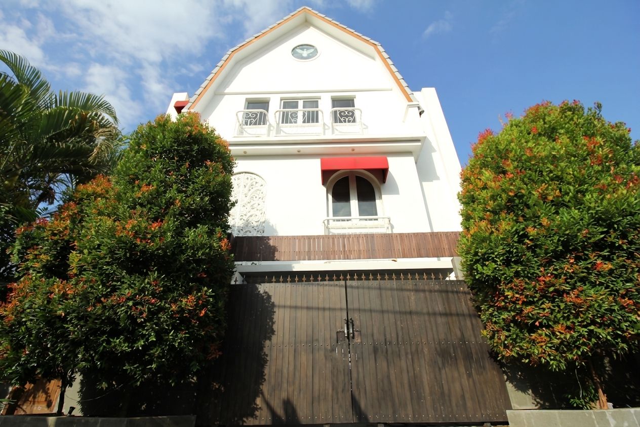 A two-story building with a red awning, a balcony with white railings, and a large metal gate.