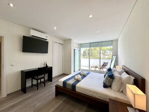 A modern bedroom with a bed, bedside table, and a desk with a chair. - VILAMOURA DELUXE 2 WITH POOL by HOMING (Vilamoura)