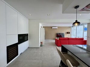 A modern kitchen with white cabinets, a built-in oven, and a dining area with a bench and table. - VILAMOURA DELUXE 2 WITH POOL by HOMING (Vilamoura)