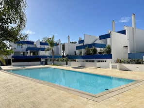 A modern building with a pool, featuring a clear blue sky and a well-maintained lawn. - VILAMOURA DELUXE 2 WITH POOL by HOMING (Vilamoura)