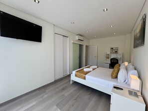 Habitación de hotel moderna con cama, mesita de noche, televisor y puerta que da a un baño.