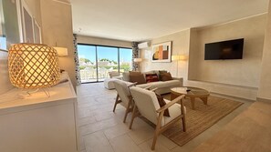 A modern living room with a sofa, chairs, a coffee table, and a TV mounted on the wall. - VILAMOURA GOLF VILLA 4 WITH POOL by HOMING (Vilamoura)