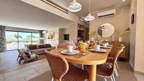 Uma sala de jantar com mesa de madeira, cadeiras de vime e disposição para café da manhã.