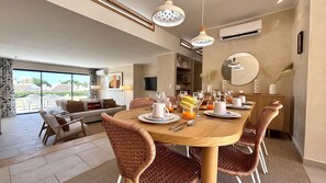 A dining area with a wooden table, wicker chairs, and a breakfast setting. - VILAMOURA GOLF VILLA 4 WITH POOL by HOMING (Vilamoura)