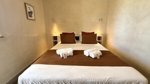 Quarto de hotel com cama, duas almofadas, mesa de cabeceira e quadro na parede.