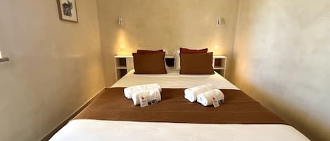 Ein Hotelzimmer mit Bett, zwei Kissen, einem Nachttisch und einem gerahmten Bild an der Wand.