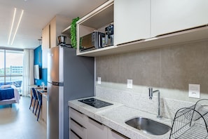 A modern kitchen with a built-in refrigerator, a sink, and a countertop with a built-in induction cooktop. - Beachclass Verano Muro Alto (Ipojuca)