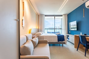 A modern hotel room with a bed, a sofa, a desk, and a TV. - Beachclass Verano Muro Alto (Ipojuca)