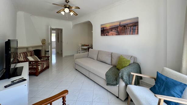 A living room with a sofa, armchairs, a television, and a ceiling fan. - VILAMOURA GOLF APARTMENT 3 WITH POOL by HOMING (Vilamoura)