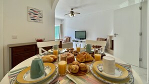 A dining area with a table set for breakfast, including croissants, muffins, and juice. - VILAMOURA GOLF APARTMENT 3 WITH POOL by HOMING (Vilamoura)