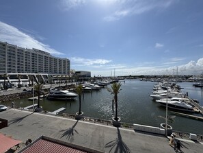 Ein Yachthafen mit vertäuten Booten, ein Hotel mit moderner Fassade und ein klarer Himmel.