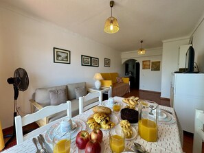 A dining area with a table set for breakfast, including bread, pastries, apples, and orange juice. - VILAMOURA CLASSIC 3 WITH POOL by HOMING (Vilamoura)