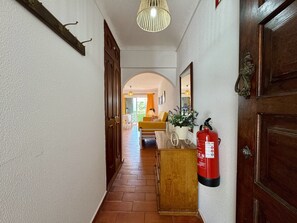 A hallway with a fire extinguisher, wooden doors, a mirror, and a hanging light fixture. - VILAMOURA CLASSIC 3 WITH POOL by HOMING (Vilamoura)