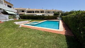 Una propiedad residencial con piscina, césped cuidado y una casa grande con varios balcones.