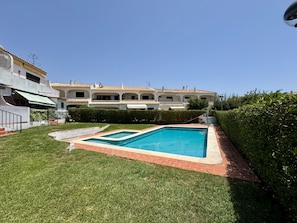 A residential property with a swimming pool, a well-maintained lawn, and a large house with multiple balconies. - VILAMOURA CLASSIC 3 WITH POOL by HOMING (Vilamoura)