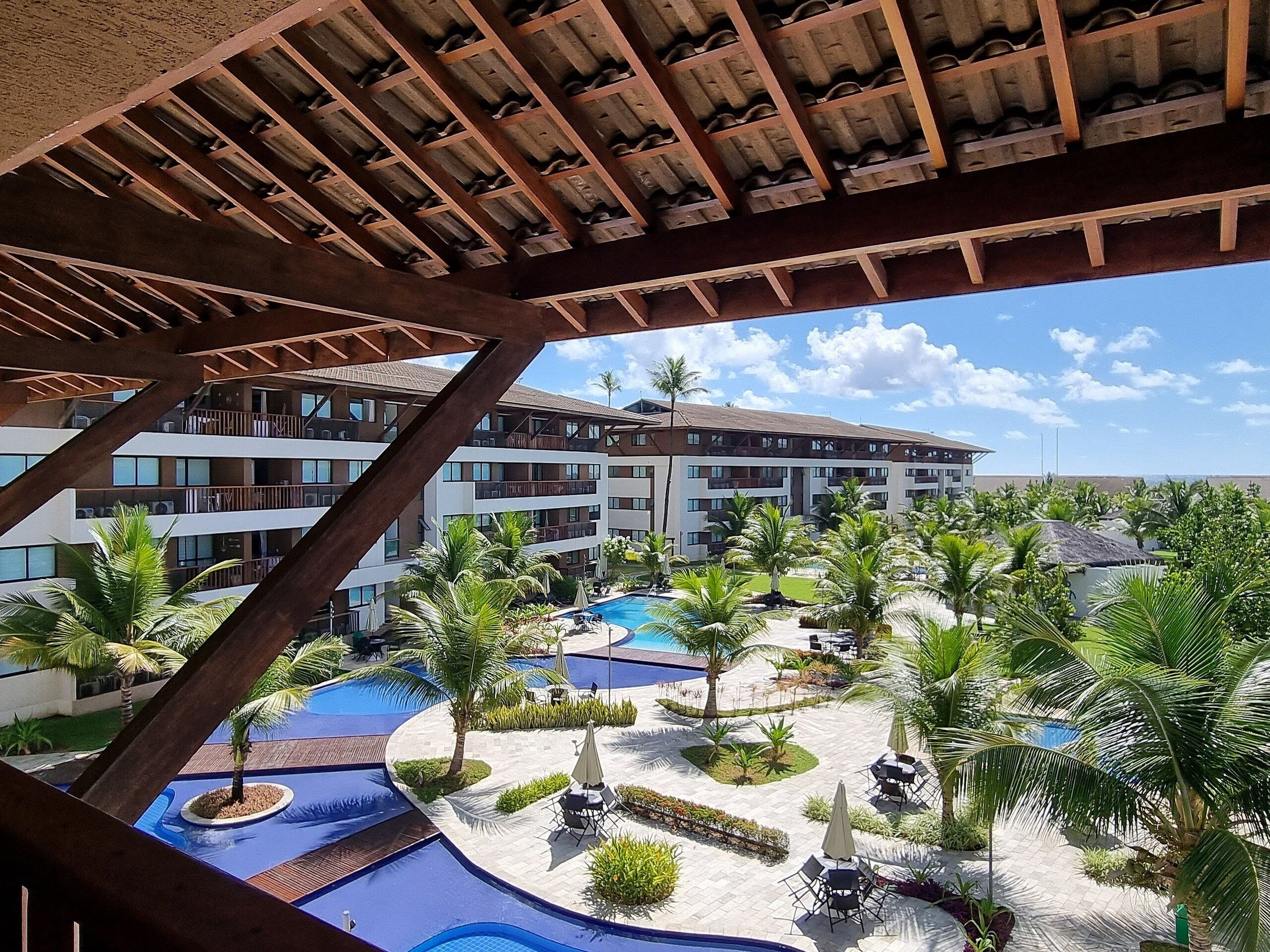 Un resort con varias piscinas, palmeras y un edificio con balcones.