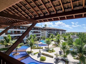 Un resort con varias piscinas, palmeras y un edificio con balcones.