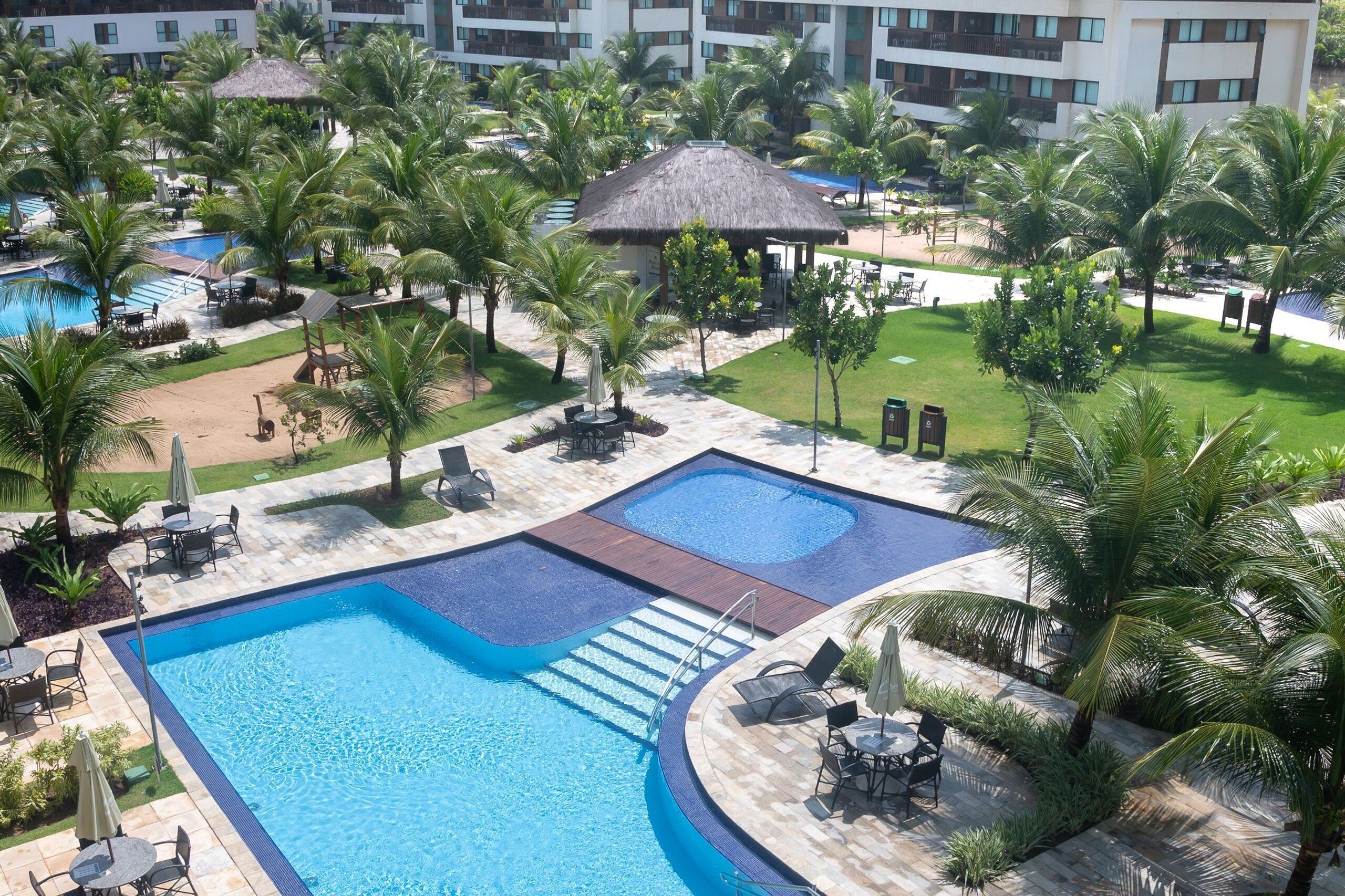 Un complex hoteler amb una gran piscina, zones d'estar i palmeres.