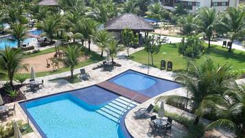 Un complex hoteler amb una gran piscina, zones d'estar i palmeres.