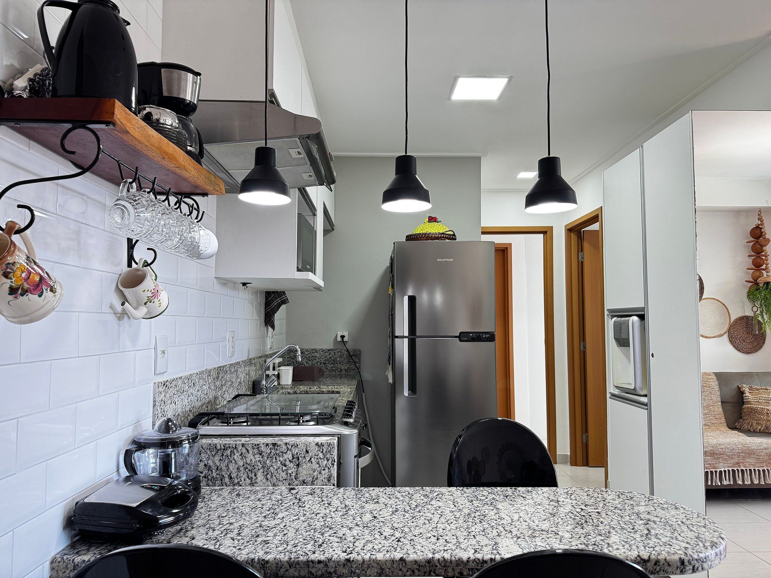 A modern kitchen with a granite countertop, stainless steel appliances, and pendant lighting.