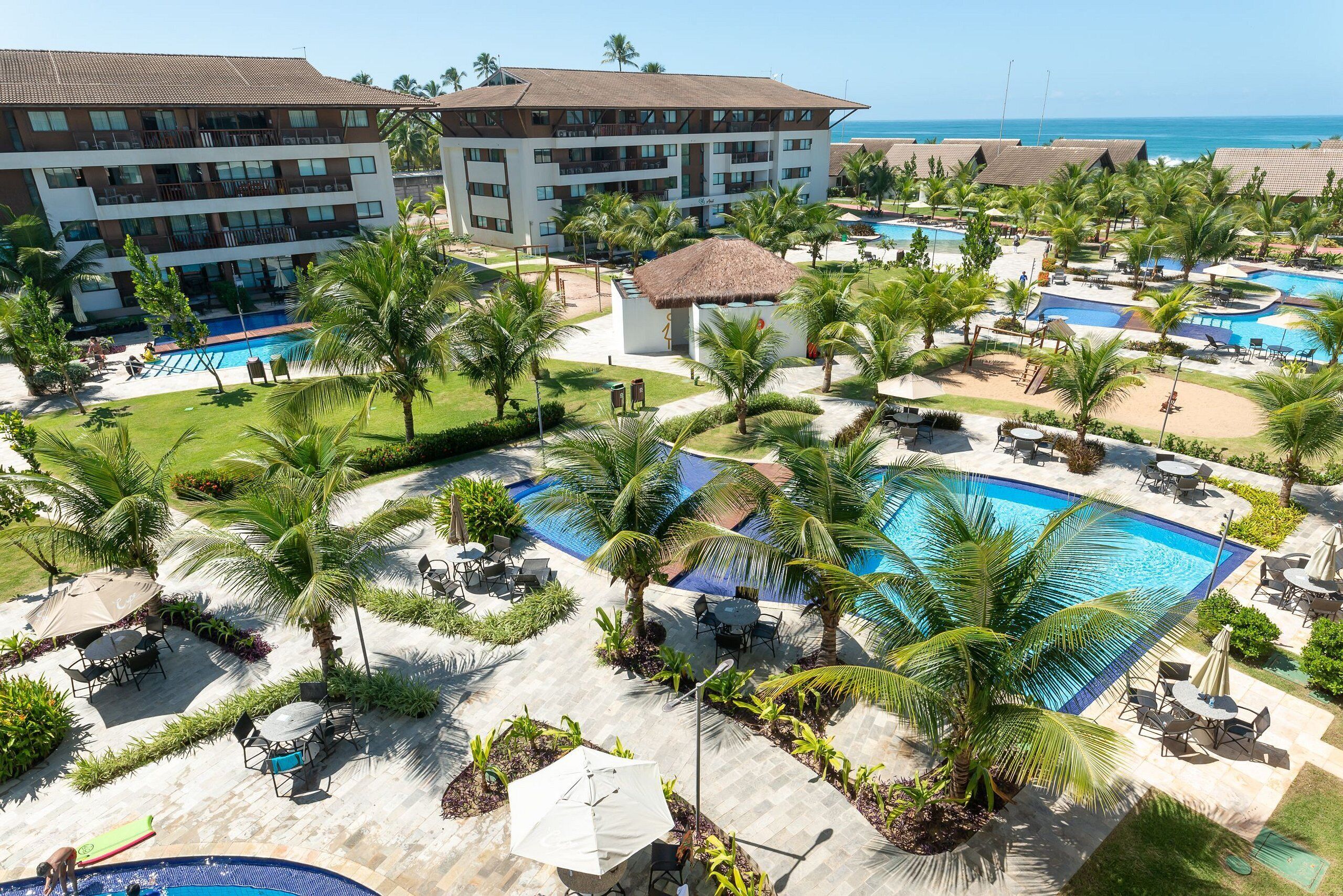 A resort with multiple swimming pools, palm trees, and a large building with balconies.