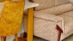 Una habitación con un sofá color beige, una mesa de madera y una silla amarilla.
