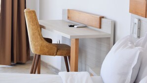 Una habitación de hotel con cama, escritorio, silla y aire acondicionado.