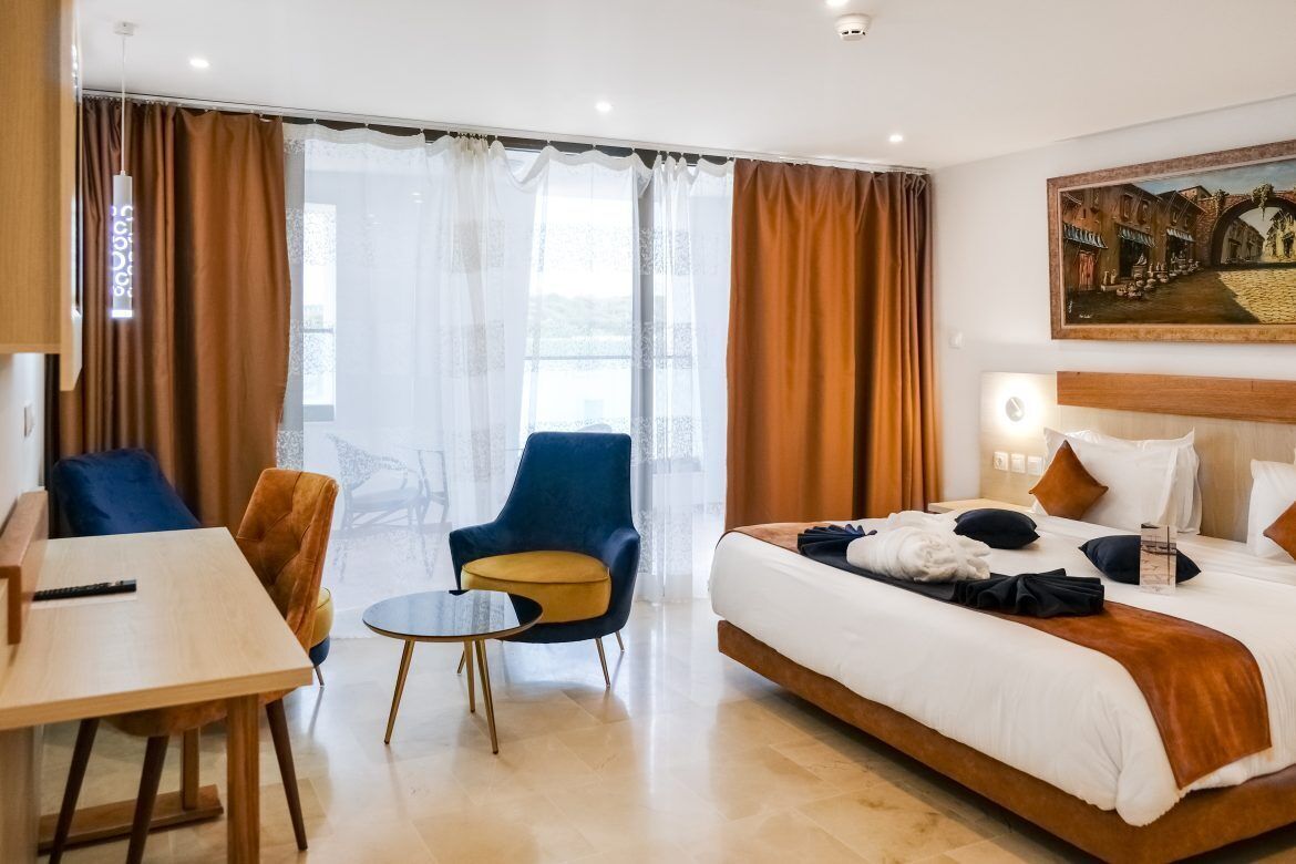 Une chambre d’hôtel équipée d’un lit, d’un bureau, d’une chaise et offrant une vue sur l’extérieur.