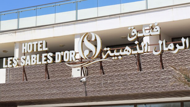 Un cartel de hotel con texto en inglés y árabe, que indica el nombre del hotel.