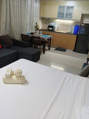 Ein Hotelzimmer mit Bett, einer Couch, einem Esstisch und einer Küchenzeile.