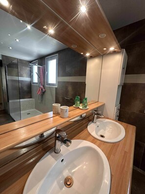 A modern bathroom with two sinks, a large mirror, and a shower area. - T2 tout confort avec terrasse de 30 m² et Wi-Fi – Proche plage de Canet (Canet-en-Roussillon)