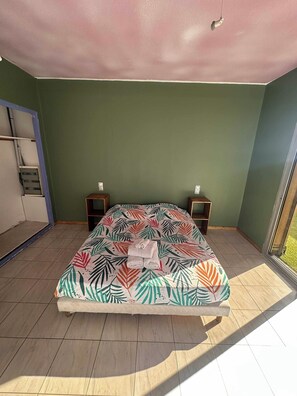 Ein Schlafzimmer mit einem Bett, zwei Nachttischen, einem Kleiderschrank und einem Fenster.