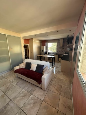 A compact living space with a sofa, a kitchenette, and a dining area. - T2 tout confort avec terrasse de 30 m² et Wi-Fi – Proche plage de Canet (Canet-en-Roussillon)