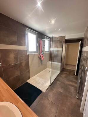 A modern bathroom with a glass shower enclosure, a bathtub, and a toilet. - T2 tout confort avec terrasse de 30 m² et Wi-Fi – Proche plage de Canet (Canet-en-Roussillon)