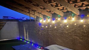 An outdoor seating area with wooden benches and a string of colorful lights. - T2 tout confort avec terrasse de 30 m² et Wi-Fi – Proche plage de Canet (Canet-en-Roussillon)