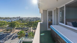 En balkon med udsigt over bybilledet, en pool og en seng med puder.