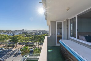 A balcony with a view of a cityscape, a pool, and a bed with pillows. - Ocean View Apartment near V&A Waterfront (Cape Town)