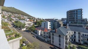 A residential area with modern buildings, a street, and a hillside in the background. - Ocean View Apartment near V&A Waterfront (Cape Town)