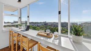 A modern kitchen with large windows, a laptop, and a coffee setup. - Ocean View Apartment near V&A Waterfront (Cape Town)