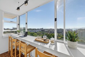 A modern kitchen with large windows, a laptop, and a coffee setup. - Ocean View Apartment near V&A Waterfront (Cape Town)