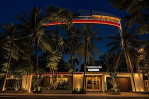A hotel with a curved facade, palm trees, and a sign indicating it is serviced by OYO.