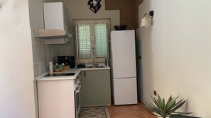 A compact kitchen with a refrigerator, stove, and sink. - Through the Alleys of Girgenti (Agrigento)